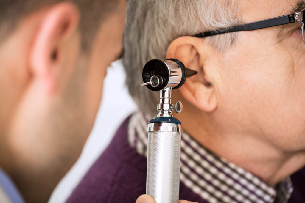 Doctor examining a man's ear canal.